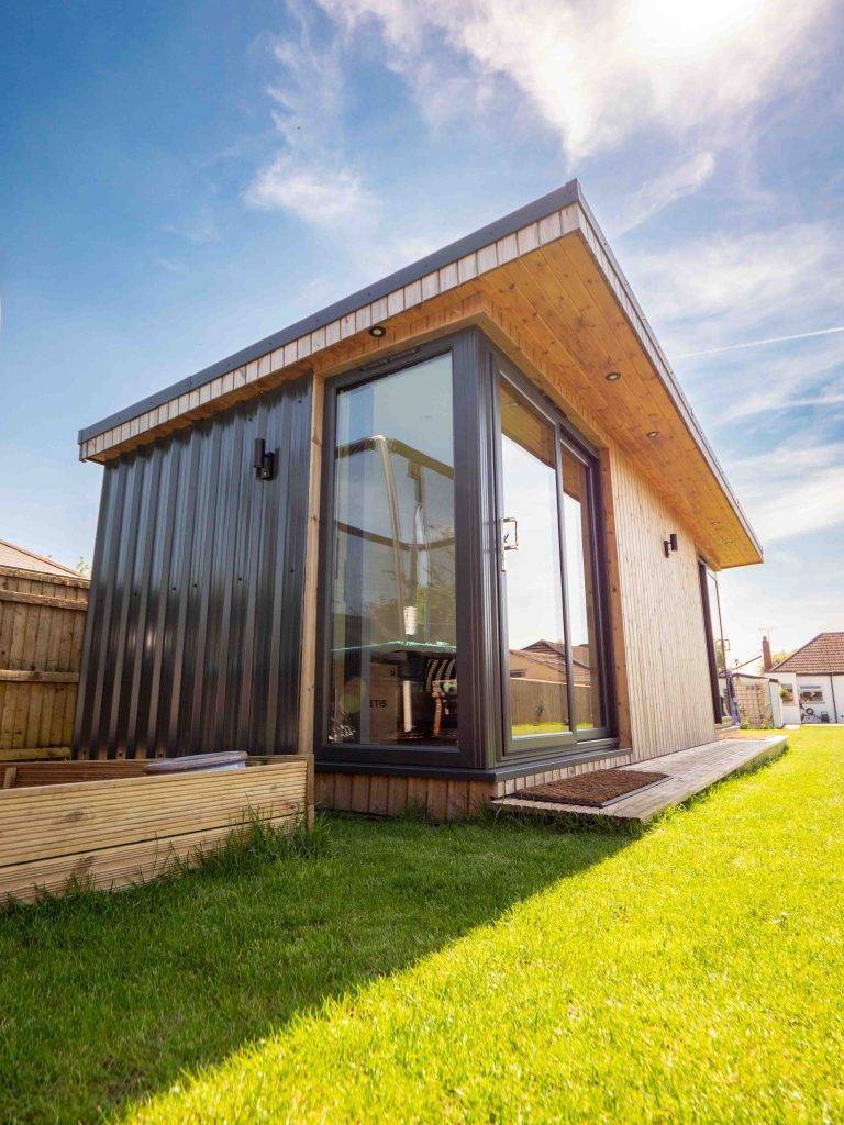 Black-clad bespoke garden room with a pent roof and full-height glazing