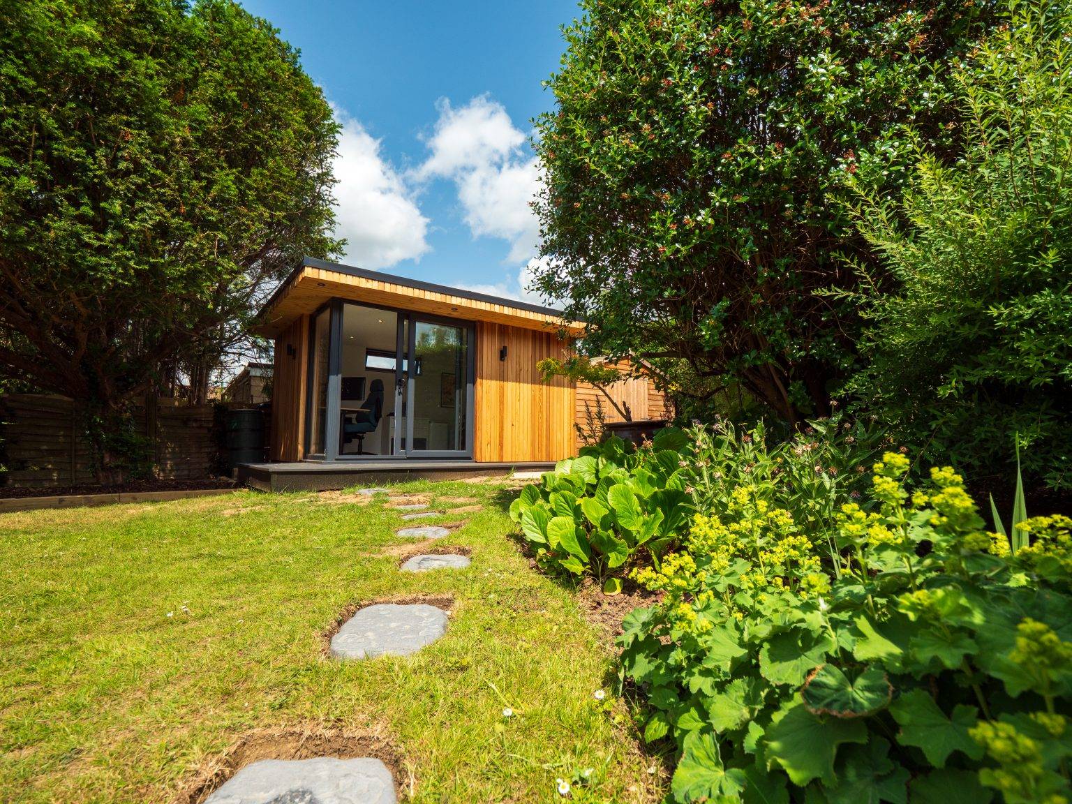 Cedar garden room at the end of a lawned garden with planting