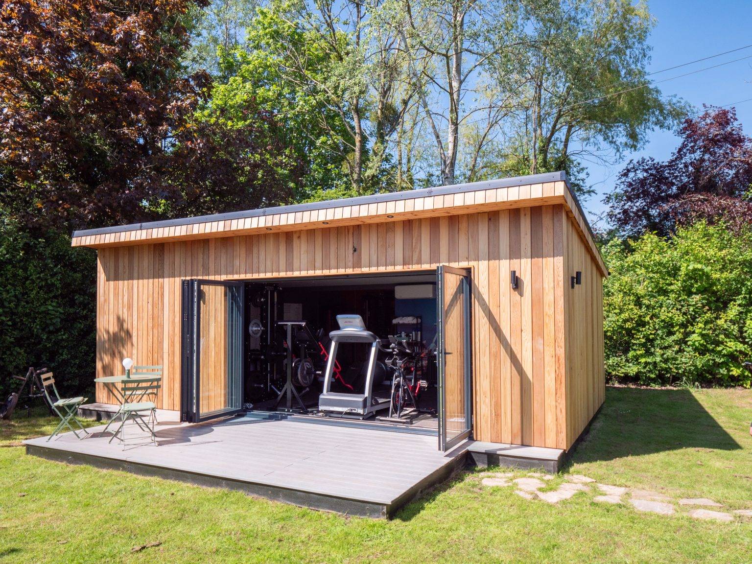 Cedar garden gym with bi-fold doors open onto grey decking